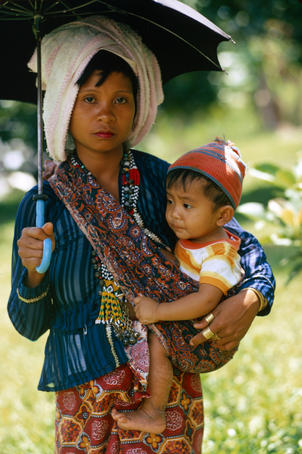 T'boli mother and son in the shade of an umbrella.