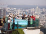 People around circular bar at Sirocco, with city buildings beyond.