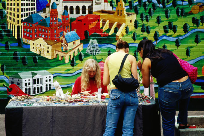 Women shopping at Renaissance Market, with mural on wall behind, Guadalupe Street.