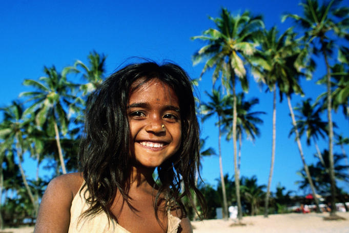 Portrait of young girl on beach with palm trees behind Colva
