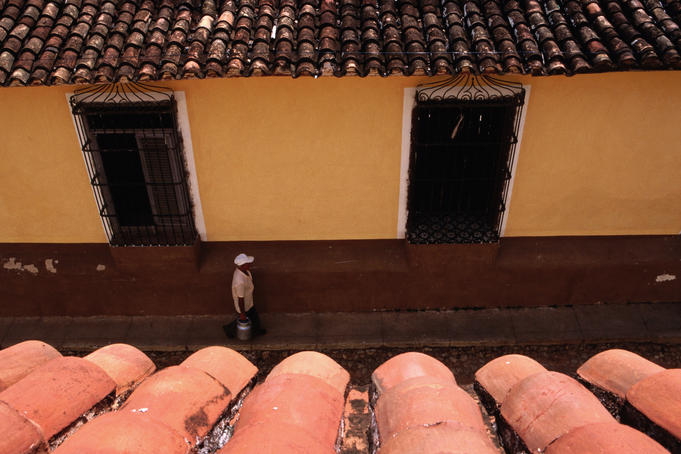 Overhead of roof tiles and man walking on cobbled street.