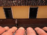 Overhead of roof tiles and man walking on cobbled street.