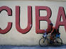 Man with dog riding past 'Cuba' mural.