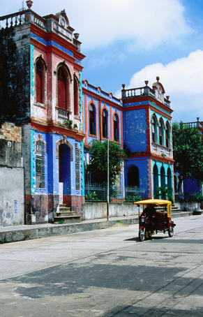 Brightly coloured buildings and motorcycle taxi.