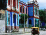 Brightly coloured buildings and motorcycle taxi.