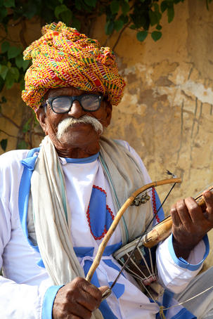 Portrait of Rajasthani man with turban playing traditional Indian stringed instrument, Sarangi.