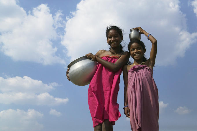 Low angle view of Indian girls carrying water jars.