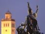 Statue in Dobo Istvan Ter commemorating 1552 Turkish siege with floodlit tower in background.