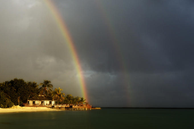 Rainbows over Full Moon resort bar during shower.