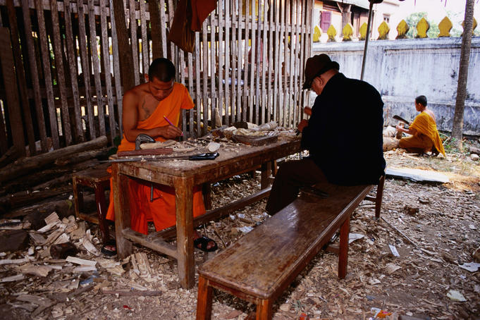 Monks work on Buddhist sculptures at art school in grounds of Wat Xieng Muan.