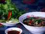 Lao-style noodle soup with shrubbery green sand peanut sauce.