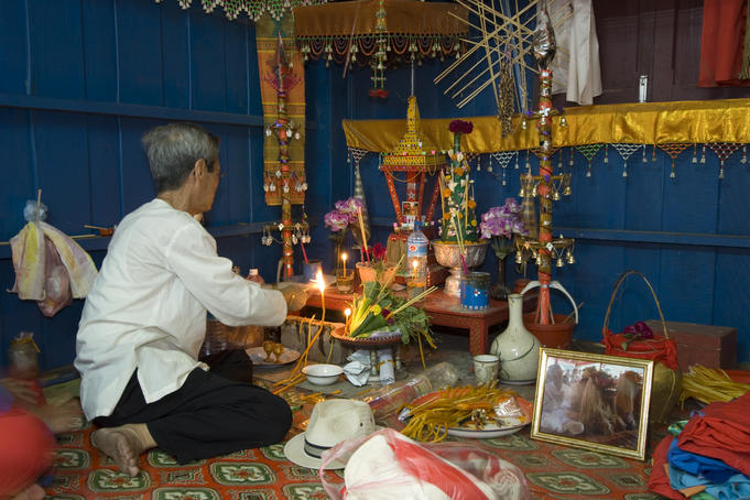 Man preparing offerings in spirit house of Peu Nyeu and Nya Nyeu, Wat Aham.