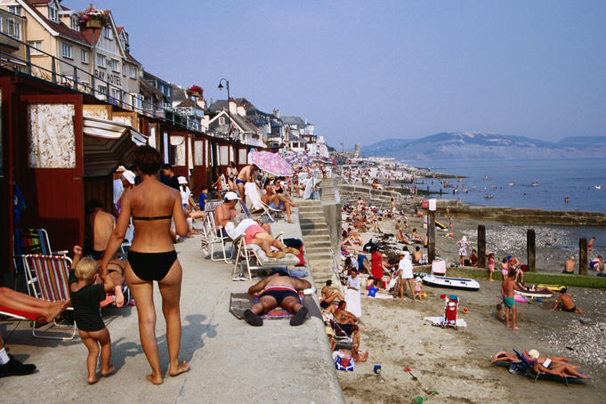 Crowed beach lined with bathing boxes.