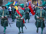 Traditionally dressed men parade through streets.