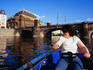 Woman paddling boat on Vltava River near National Theatre.