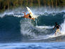 Brazilian surfer doing radical backhand re-entry while local surfer looks on.