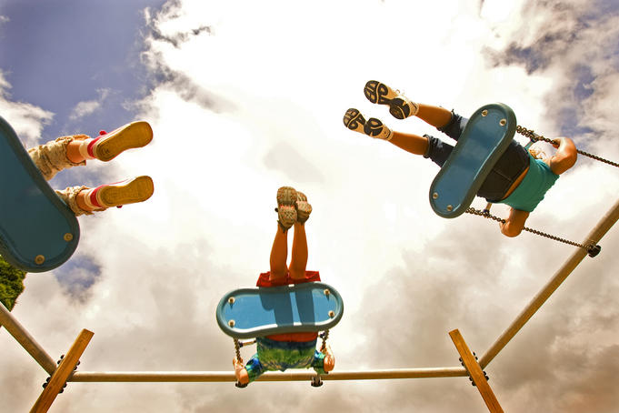 Children playing on swings from below.