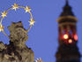 Floodlit statue of saint on plague column against tower with red lights in Velke Namesti Square.
