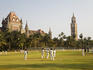 Playing cricket on Oval Maidan with High Court in background.