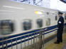 Railway employee monitors departure of shinkansen bullet train bound for Toyko.