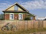 Bicycle against wooden fence of house.