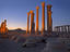 Part of illuminated colonnade ruin with Qala't ibn Maan (castle) on the hilltop behind.