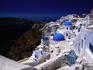 White-washed houses and blue domes on cliff top.