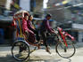 Two people travelling by rickshaw.