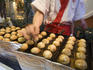 Cook prepares tako-yaki, octopus balls, Dotombori.