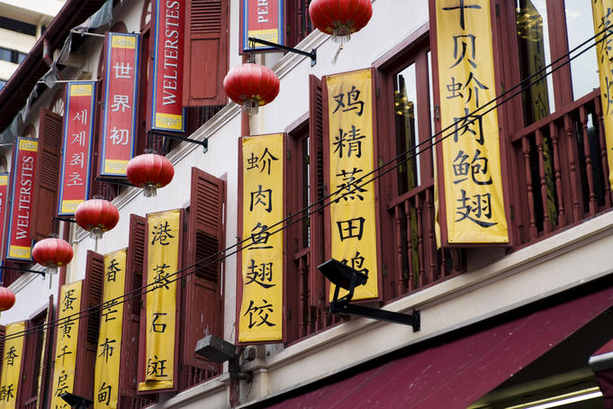 Shuttered windows with Chinese written signs attached.