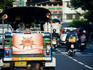 Tuk-tuk and motorcycles on city street.