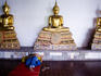 Buddhist statues and sleeping person in temple.