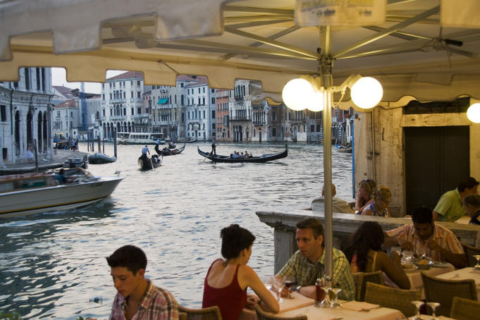 Alfresco diners on bank of Grand Canal near Rialto Bridge.