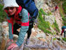 Hiker using old tree root as stairway on GR20 walking trail.