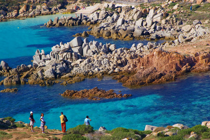 Tourists admiring blue waters of Corsica's coastline.