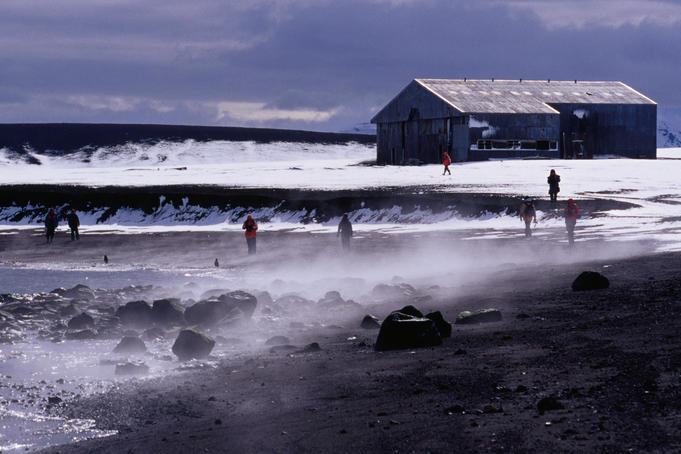 Tourists on beach in front of derelict aircraft hangar, Whalers Bay.