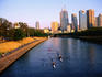 Rowers on Yarra River with city skyscrapers in background.