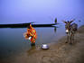 Woman washing dishes by Niger River at dusk.