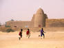 Children playing football with cotton ball in front of mosque.