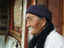 Portrait of Dr Ho, a noted herbalist well known to foreign visitors outside his clinic in Baisha Village.