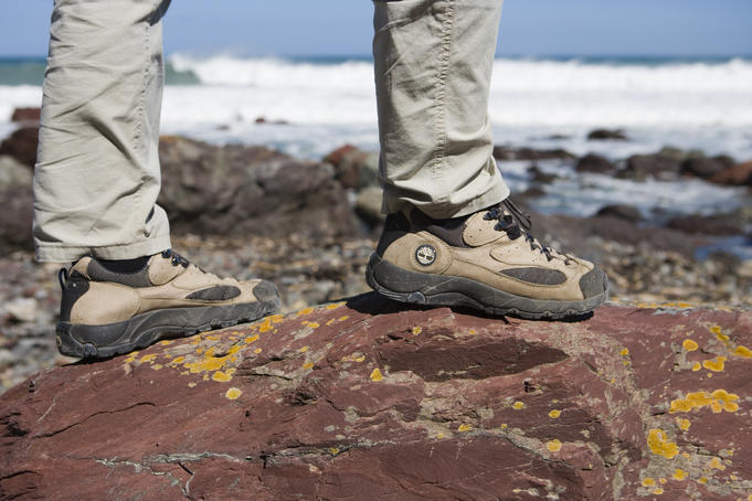 Hiker on rock on Red Rocks Coastal Walk. Sensibl.e