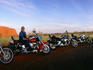 Harley Davidsons and riders at sunset with Uluru in background.