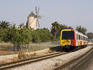 Train passing by windmill.