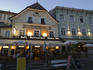 Restaurants in old town houses lining Rathausplatz at dusk.