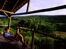 Man relaxing on hotel balcony and looking over grasslands.