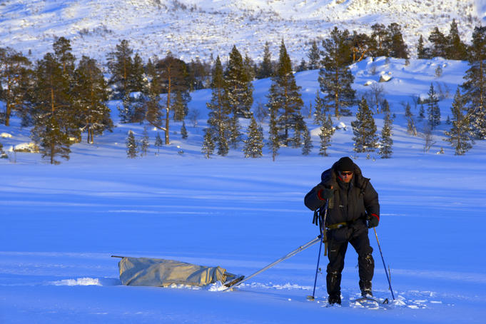 Trekking through the snow pulling a sledge.