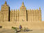 Young boy with donkey cart in front of the Grande Mosque du Djenne.