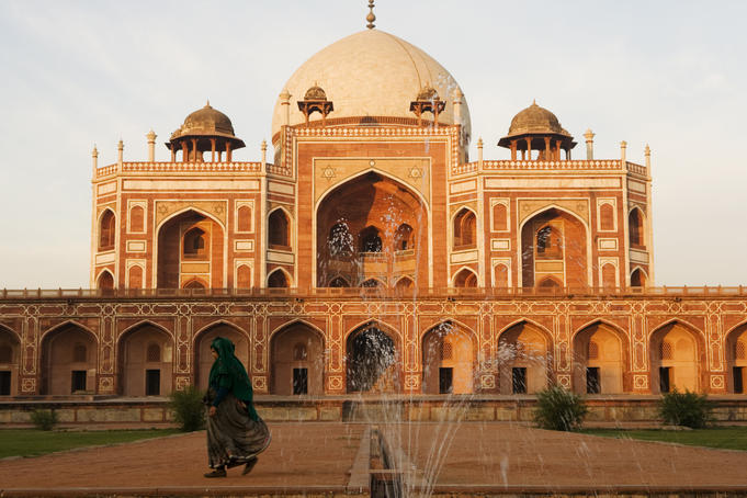 Woman wearing sari walking past Humayun's tomb in New Delhi.