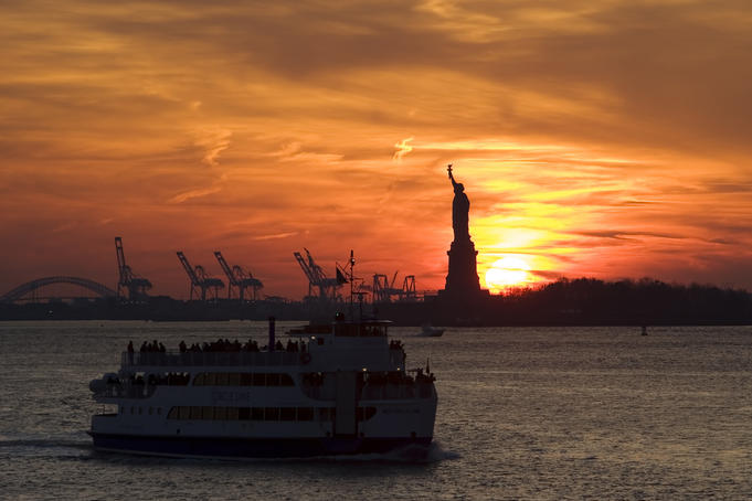 Statue of Liberty and Staten Island Ferry at sunset.