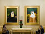 Two female tourists sitting under paintings of sheikhs at Emirates Palace Hotel.